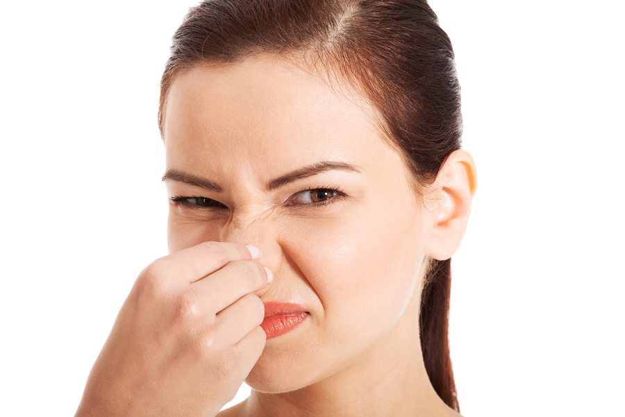 Portrait of a young woman holding her nose because of a bad smell. Isolated on white.